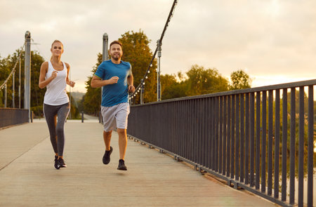 Two runners in the evening. Young boyfriend and girlfriend having a jogging workout on city streets....