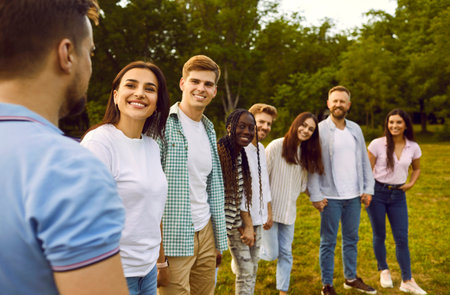 Happy young diverse friends meet in the park in summer. Several young people having fun in nature...