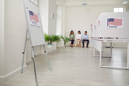 Polling station with a row of white voting booths decorated with American flag at vote center....