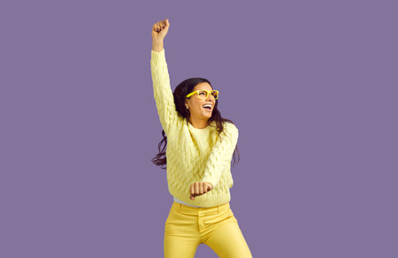 Overjoyed millennial ethnic girl isolated on violet studio background dancing and laughing. Smiling...