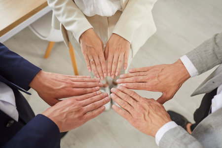 Three business partners put their hands together as symbol of unity, motivation and cooperation. Close up of hands of business colleagues standing in circle. Concept of people and business. Top view.の写真素材