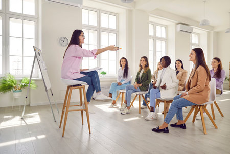 Group of multinational business women company employees sitting on chairs in a row on a meeting and...