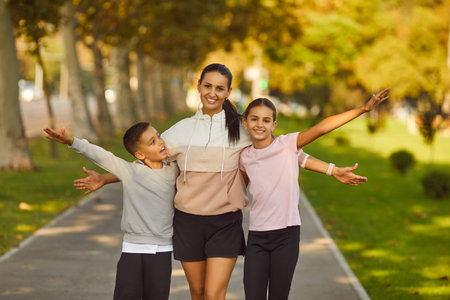 Portrait of happy smiling sporty family of mother and her children boy and girl wearing sportswear looking cheerful at camera after workout in park. Outdoors training and healthy lifestyle concept.の写真素材