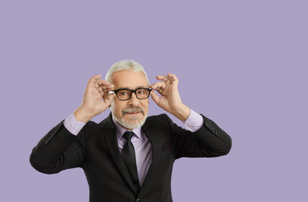 Portrait of happy handsome bearded white haired senior man dressed in classic black suit and stylish...