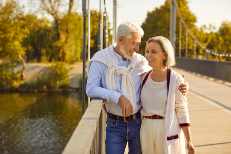 Smiling and happy senior couple enjoys a leisure walk in the city park. They radiating happiness and warmth. This snapshot captures a moment of shared bliss during a vacation or holiday.の写真素材