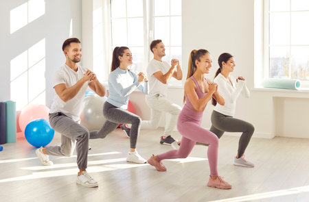 Group of athletes, together doing synchronized workout session and squats at the gym. They perform sport, fitness exercise, showcasing the unity and teamwork essential in active fitness journey.の写真素材
