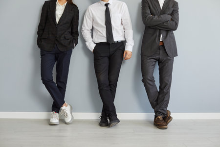 Business team in office clothes. Group of people wearing formal suits and casual shoes standing by a...