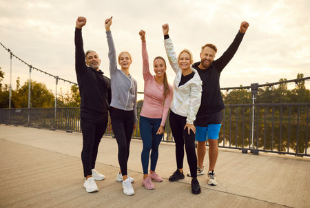 Full length portrait of a group of friends in a city park. The sports team demonstrates the essence of people unity and the joy of training or fitness in nature as they smile together.の写真素材