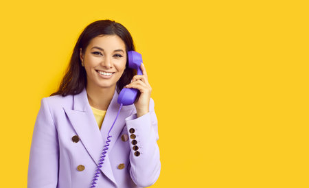 Happy stylish woman making phone call. Beautiful young business lady in trendy lilac jacket standing...
