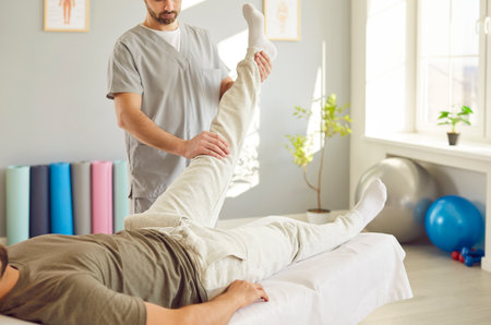 Skilled masseur provides a rejuvenating leg massage for a man on a therapy couch at a spa salon. Health focused treatment, expert techniques to enhance relaxation and well being.の写真素材