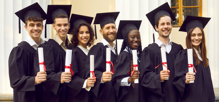 Portrait of a group of smiling happy diverse multiracial graduates students standing in a line in a...