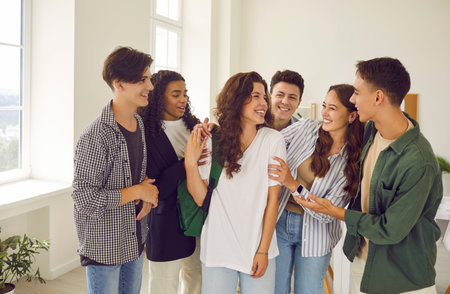 Group of happy smiling diverse friends in the classroom. Cheerful teenage multiethnic boys and girls meet after class, share news, discuss school and have fun togetherの写真素材