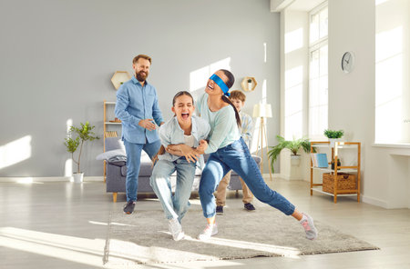 Happy family with children is playing hide and seek at home in the living room. They are enjoying...