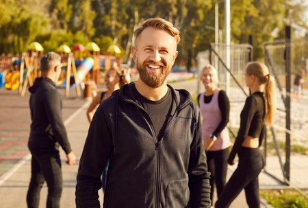 Portrait of happy bearded cheerful man looking at camera after doing sport fit exercises in the city...