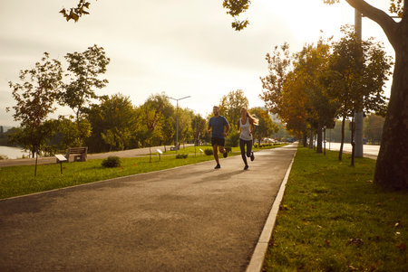 Happy smiling sporty couple wearing sportswear jogging in the park having sport workout. Young man...