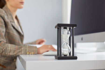Close up of sand glass on desk of busy office worker trying to meet deadline. Closeup of hour glass...