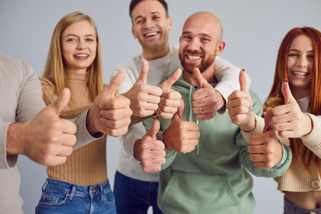 Group of diverse individuals showcases beaming smiles as they collectively raise their hands with...