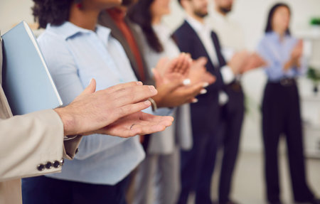 Group of diverse young people men and women applauding standing in a row. Successful coworkers and company employees clapping a colleague on a meeting or business conference. Selective focus.の写真素材