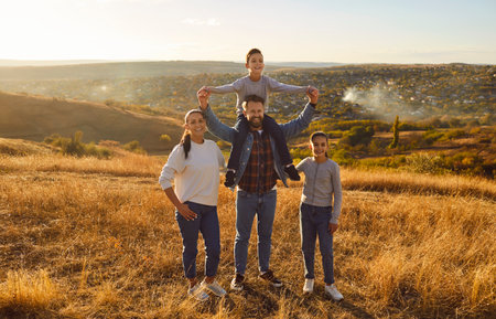 Portrait of happy smiling young family with son and daughter standing outdoors enjoying beautiful...