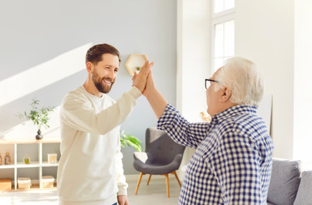 Family together happy senior father and adult son high-fives celebrating joys of fatherhood. Fatherhood happiness paternal love shared happiness within family Father and son fatherhood happy familyの写真素材