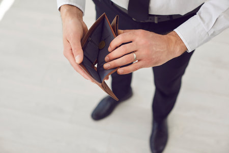 Top view of poor business man person wearing formal clothes holding an empty wallet in hands with no...