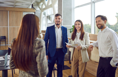 Office workers have friendly conversation with each other during working day in office. Smiling male...