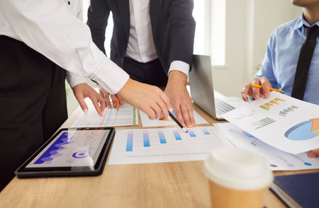 Group of business people standing on workplace in meeting room discussing company finance growth...