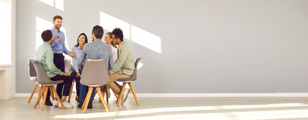 Business coach and team mentor meeting with group of people. Smiling man talking to happy young...
