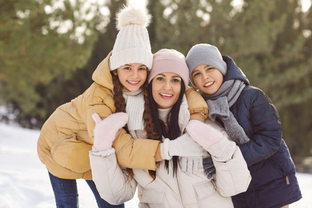 Portrait of a happy, smiling Caucasian mother with her children during a winter walk in the forest....