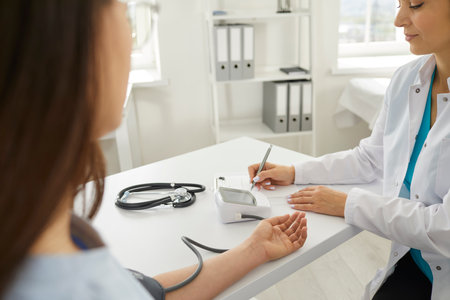 Doctor cardiologist or nurse measuring a patient blood pressure using a sphygmomanometer during a consultation in the hospital. Medical checkup ensures proper healthcare and patient well being.の写真素材