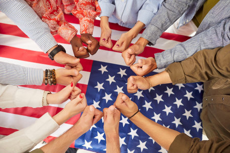 Top view of multiethnic people hands showing thumbs up over large american flag. Group of...