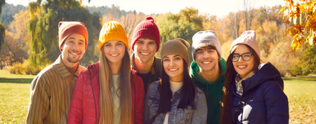 Happy friends enjoying fall season. Joyful young people in warm casual jackets and colourful knitted...