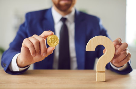 Man holding a bitcoin coin and a question mark sign, symbolizing curiosity in the cryptocurrency, finance, online trading strategies. Exploration digital money investments in the business world.の写真素材