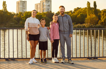 Group portrait of a happy family with children standing together after an active fitness workout in the city park. They smile and look at the camera, joy after sport exercising outdoors.の写真素材