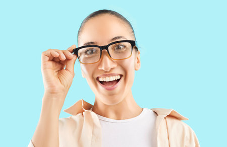 Portrait of a happy and excited Caucasian woman in glasses, exclaiming wow against a blue...