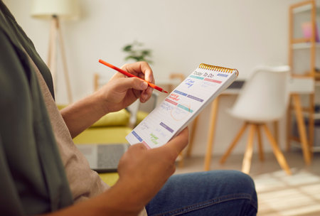 Man sitting on sofa at home or at office with pen in hand planning tasks and to do list in his...