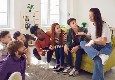 Young people diverse group portrait, happy students friendly chat, sitting on sofa talking, discussing study, graduation, sharing youth experiences, feelings and ideas, positive communication skillsの写真素材