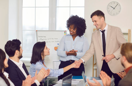 Businesspeople meeting represent, diverse workers support new employee, staff sitting at desk clap hands, take part in promotion, successful teammate support, career growth, professional achievementの写真素材