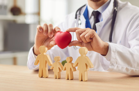 Close up shot of a doctor or nurse holding a red heart with wooden family figures, protection and care in a medical setting. Cardiology and healthcare in a hospital or clinic.の写真素材