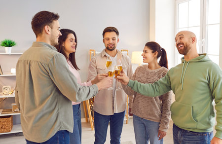 Group of young friends toasting wine glasses and talking standing in a circle together at home. People cheering with glass of champagne celebrating birthday at home party. Celebration concept.の写真素材