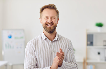 Portrait of a happy Caucasian young adult businessman working in the office, smiling at the camera. He is a director or boss, radiating positivity and professionalism in business environment.の写真素材