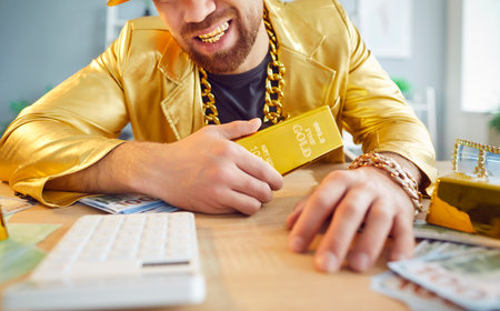 Rich, smiling man dressed in a golden suit, holding a gold bar. His attire and the gold symbolize financial success, money wealth, luxury, prosperity and growth in financial endeavors.の写真素材