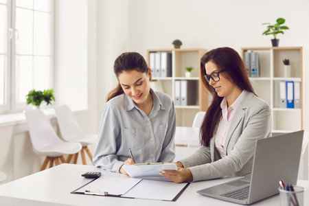 Woman customer signs a contract in the bank office. Young woman takes out a money loan and puts her signature on the paper document. Business and finance conceptの写真素材