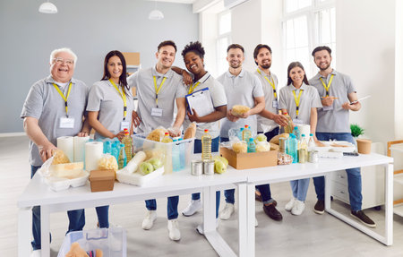 Portrait of a multicultural group of volunteers of different ages standing at a table with food....