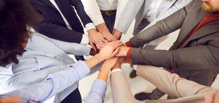 Close-up top view, stacking hands of multicultural business people standing in circle. Corporate...