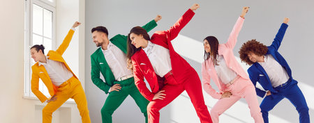 Positive and smiling group of young dancers in colorful business costumes dance together. The lively party is filled with music, colorful outfits, and a joyful crowd enjoying the dance.の写真素材