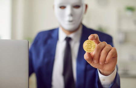 Anonymous businessman working with laptop in the office, holding a digital bitcoin. Representing finance, online secure trading, cryptocurrency, money, and investment opportunities on the internet.の写真素材