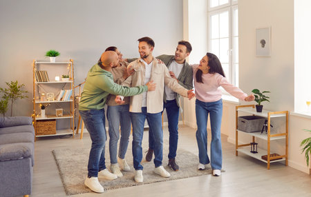 Portrait of a group of laughing happy young friends students or colleagues having fun hanging together at home. Guys and girls standing in a row, hugging and enjoying meeting. Friendship concept.の写真素材