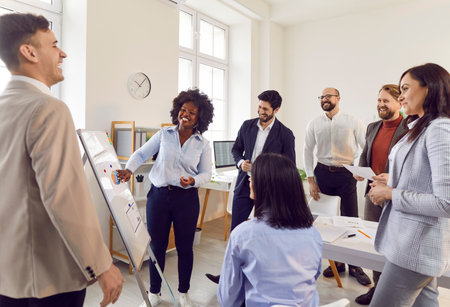 Group of diverse business people on meeting discussing work project standing in a circle in office. Company employees listening their african americam woman colleague with a report in conference room.の写真素材