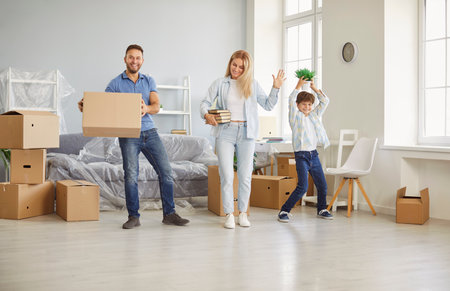 Happy family dance, new flat home owners, parents playing with cute small kid son on moving day,...